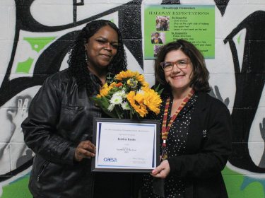 women holding a plaque and flowers together